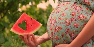 slice watermelon in the hand of a pregnant woman